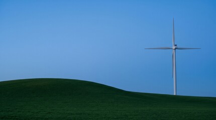 Obraz premium Single wind turbine standing on rolling green hills under a clear blue sky.