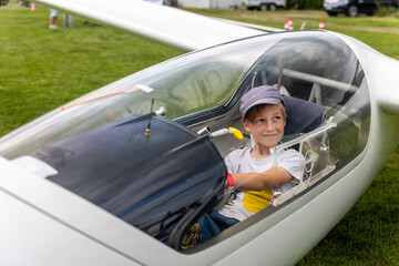 Cute little happy boy sits inside glider cockpit aviation club activity airfield. Childhood dream flying flight school experience, inspiring curiosity, learning, adventure and future aspirations © Kyryl Gorlov