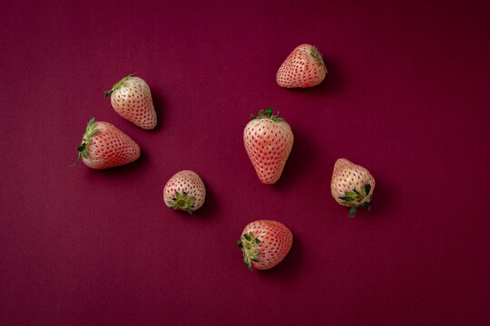 Fresh white strawberries on luxury dark burgundy red paper background