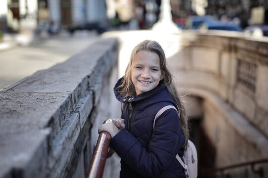 Happy young girl with a backpack on city steps