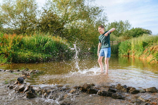 Preteen boy splashing water while playing in a stream
