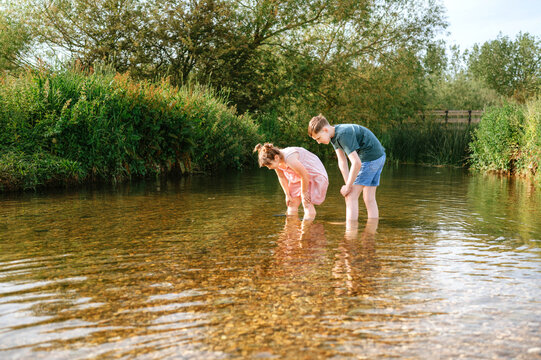 Brother and sister exploring a shallow stream together