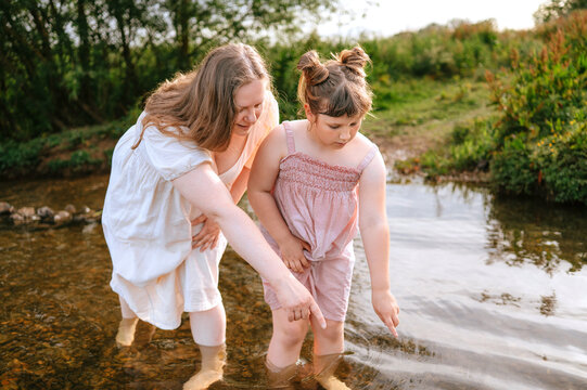 Mother helping daughter explore a shallow stream