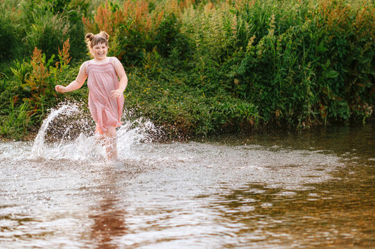 Child girl girl running through a stream and splashing water