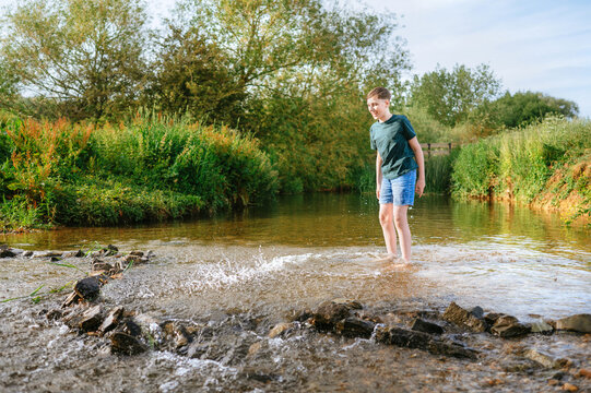 Preteen boy standing in shallow stream during summer