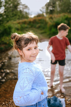Child girl looking at camera beside a countryside stream