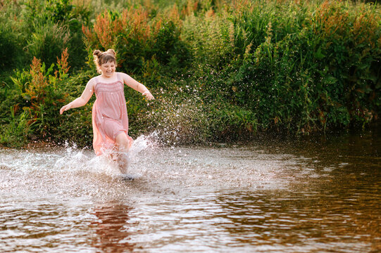 Child girl running through a stream and splashing water