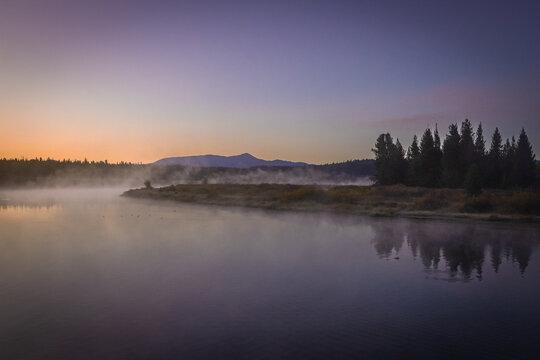 Misty Lake at Dawn With Tree Reflections and Distant Mountain Si