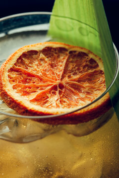 A slice of dried orange in a glass with a cocktail. Studio light.