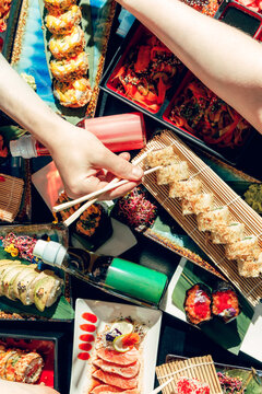 People in a sushi bar eating sushi with chopsticks.
