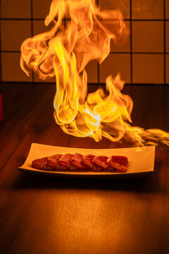 Chef in a professional restaurant kitchen sears food with a burner