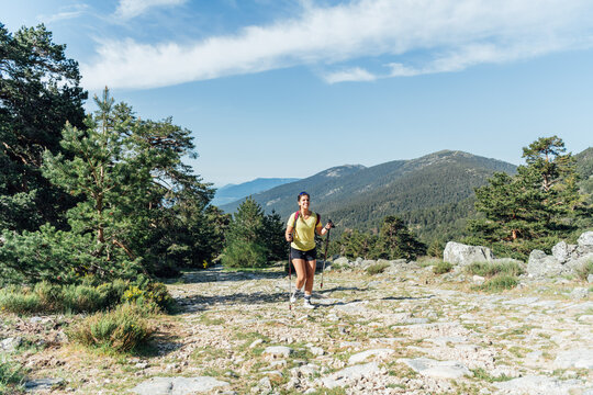 Smiling woman hiking on a sunny mountain trail