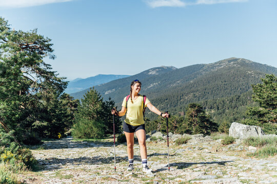 Smiling young woman hiking on a sunny mountain trail
