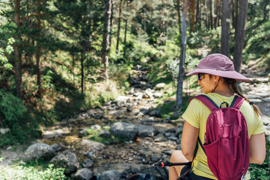 Young woman hiker rests by a rocky creek