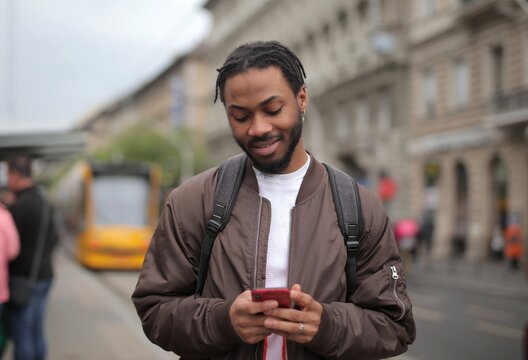Young Black man checks phone on a city street