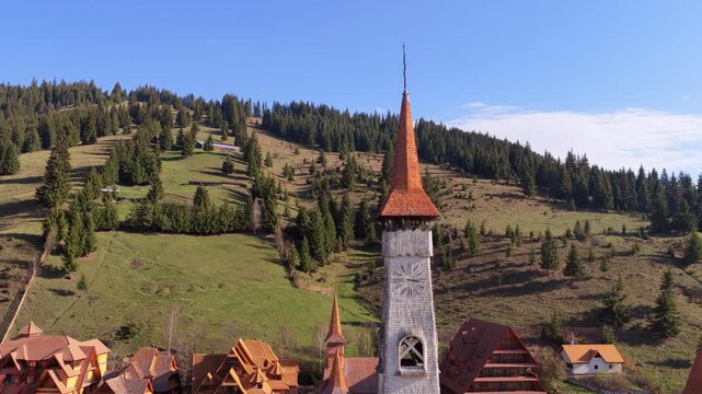 Aerial drone view of a traditional wooden church tower with a tall spire and clock in Ciocanesti, Bucovina, Romania