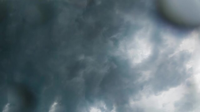 Timelapse of dark swirling storm clouds roiling in sky with rain drops