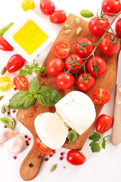 fresh mozzarella cheese with cherry tomatoes, basil and olive oil on wooden cutting board