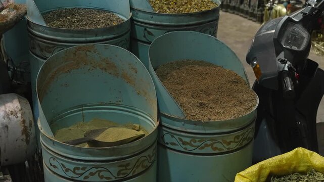 Ornate blue metal bins filled with dried spices, herbs and powder for sale in a Moroccan souk market