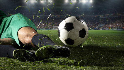 Obraz premium Soccer ball flying after slide tackle on grass field with stadium lights. Concept of defensive play, match drama, sports news, tournament ads, and dynamic football media.