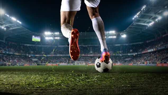 Soccer player stepping on ball during night match in stadium. Concept of ball control, tactical pause, sport footwear advertising, match promo, and team strategy visuals.