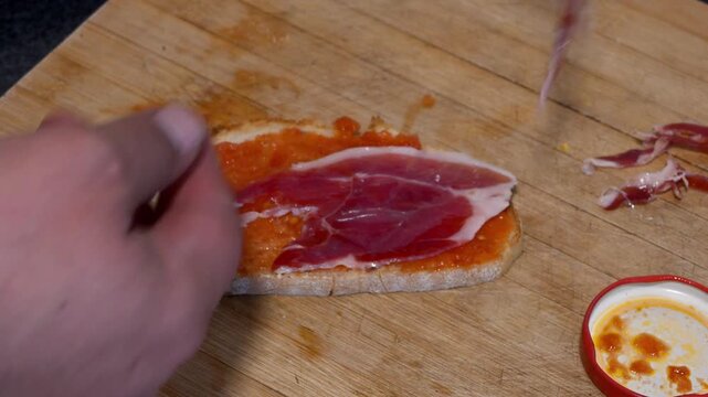 Person preparing a spanish serrano ham toast