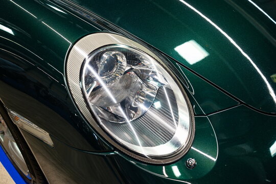 Lucerne, Switzerland, May 30, 2026. An integrated projector headlight lens on a dark green Porsche 911 997 generation car