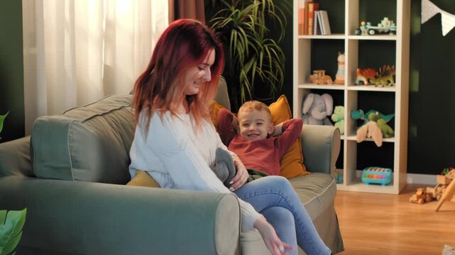 Mother taking off socks of her son on the sofa