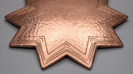 Golden metallic star-shaped badge with engraved texture on neutral background