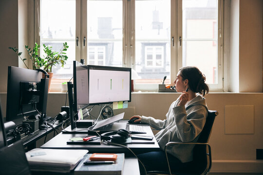 Female business expert working on dual monitor in tech startup company