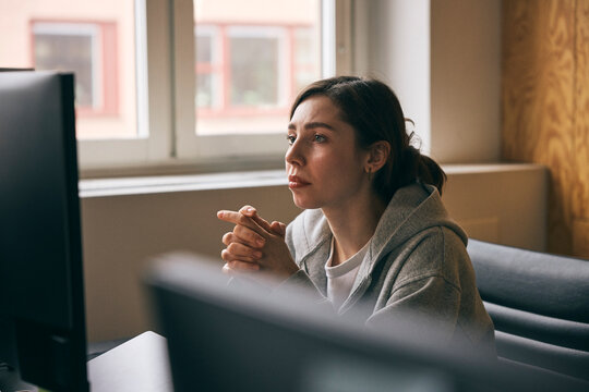 Focused female entrepreneur working on computer in startup office