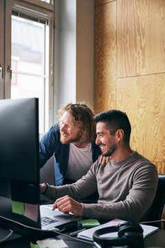 Happy male business experts working on desktop PC in tech hub