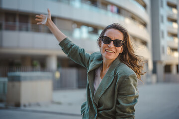 Obraz premium Happy woman raising arm hailing taxi in city