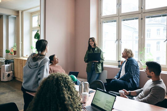 Group of male and female tech professionals discussing ideas in meeting at startup office