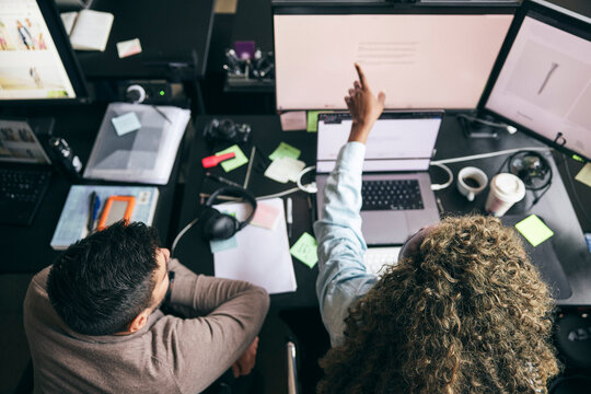High angle view of curly haired businesswoman explaining data preview to male coworker on computer while working in tech