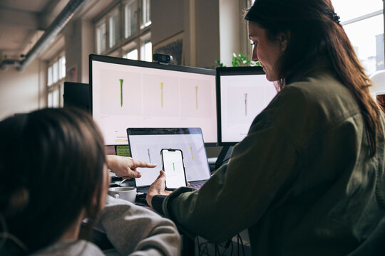 Female tech experts checking responsive design preview on all devices while working in startup office