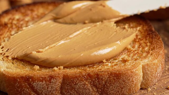 Creamy peanut butter spread on toasted bread with knife
