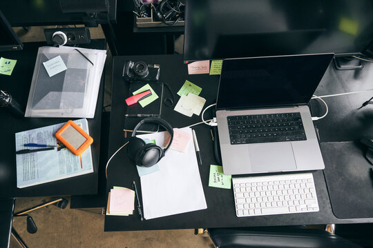 High angle view of laptop and wireless headphones kept with adhesive notes at desk in office