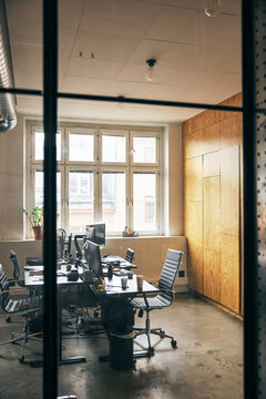 Empty office room with computers at desk seen from glass wall