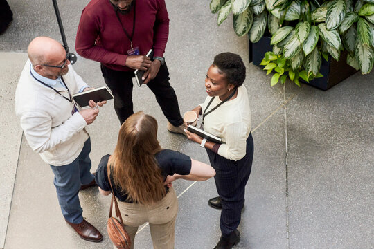 High angle view of smiling female delegate talking with business people at lobby in convention center