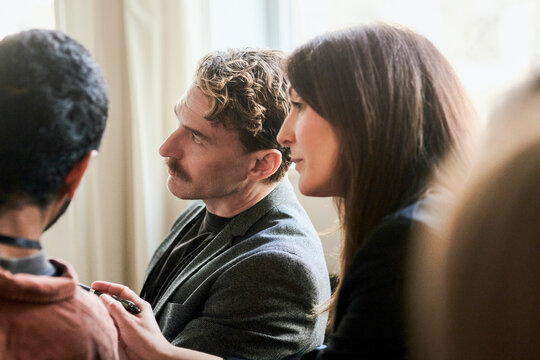 Curious male entrepreneur listening to ideas shared by associate during seminar in convention hall