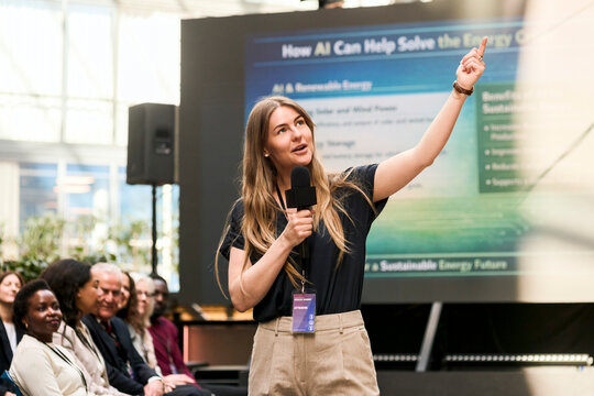 Female professional speaker addressing audience while giving presentation speech at seminar in convention center