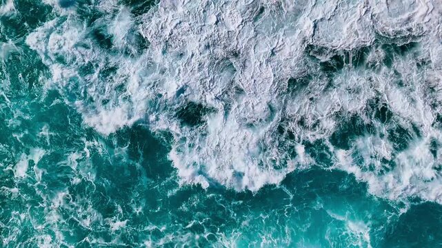 Aerial view of turbulent ocean surface with powerful waves and swirling water patterns
