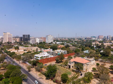 Aerial view of Frere Hall surrounded by lush green trees and the urban skyline under a clear blue sky in Karachi, Sindh, Pakistan.