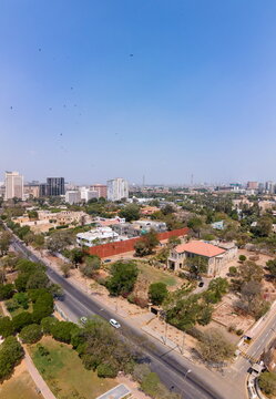 Aerial view of the historic Frere Hall area with lush green trees, urban buildings, and a busy road under a clear blue sky in Karachi, Sindh, Pakistan.