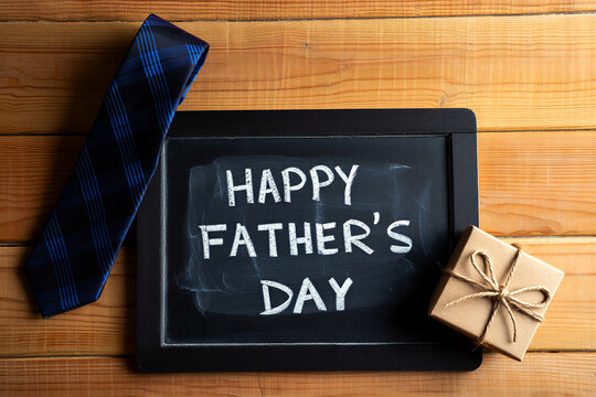 Happy fathers day celebration with tie gift and chalkboard sign on wooden table