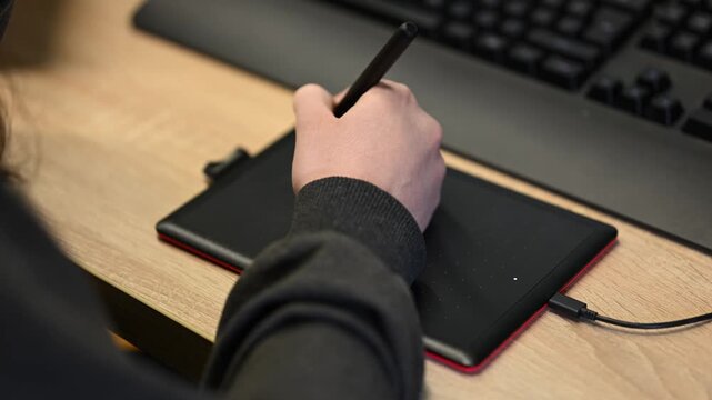 Person using graphic drawing tablet and stylus pen for digital art creation.