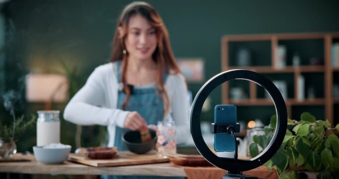 Matcha, live stream and ring light with woman in home for green tea tutorial, wellness influencer and review. Social media, content creation and health drink guide with person and phone in house