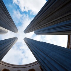Naklejka premium View of Tall Columns Against a Cloudy Sky From Below in an Open Space