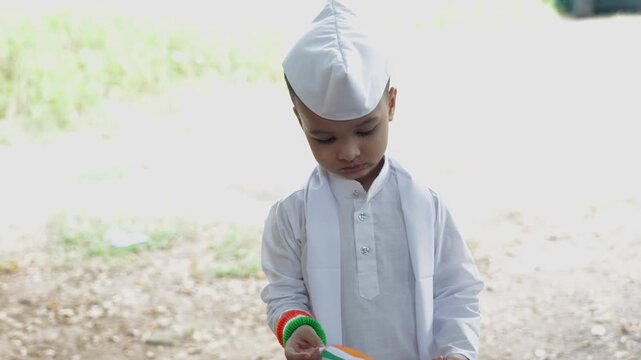 young child holding indian national flag wearing traditional white attire and gandhi cap
